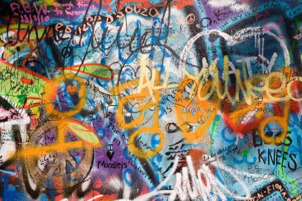 Närbild på graffiti på John Lennon-muren i Prag, en livlig färgpalett och olika konstnärliga uttryck skapar en dynamisk bild.