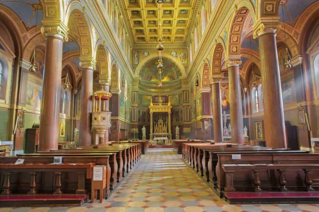 Bild inne i Sankt Kyrillos och Sankt Methodios kyrka i Prag, blickande mellan bänkraderna fram till det ståtliga altaret.